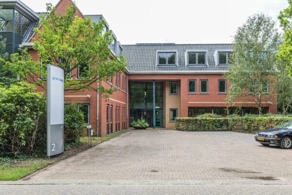 Bakstenen kantoorpand aan de Laan Blussé van Oud-Alblas 2 met entree, parkeerplaats en duidelijke bewegwijzering van GrandVision.